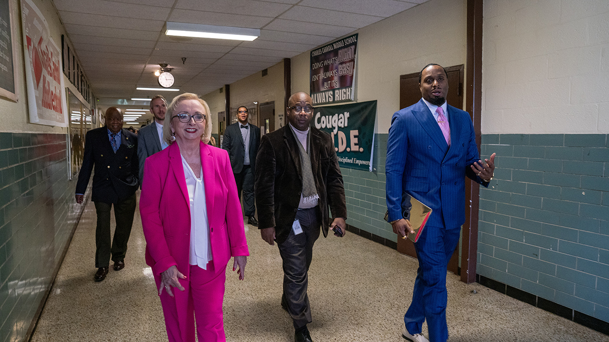 -Dr-Wright-walking with group through school hallway