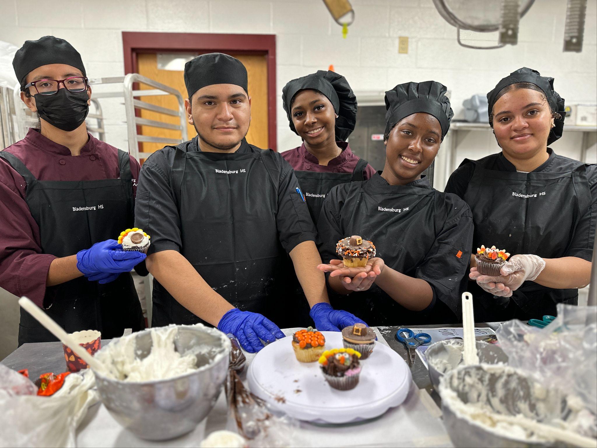 students baking holding inspired cupcakes